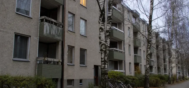Kommunalt hyreshus i Sverige med balkonger och björkträd framför fasaden
